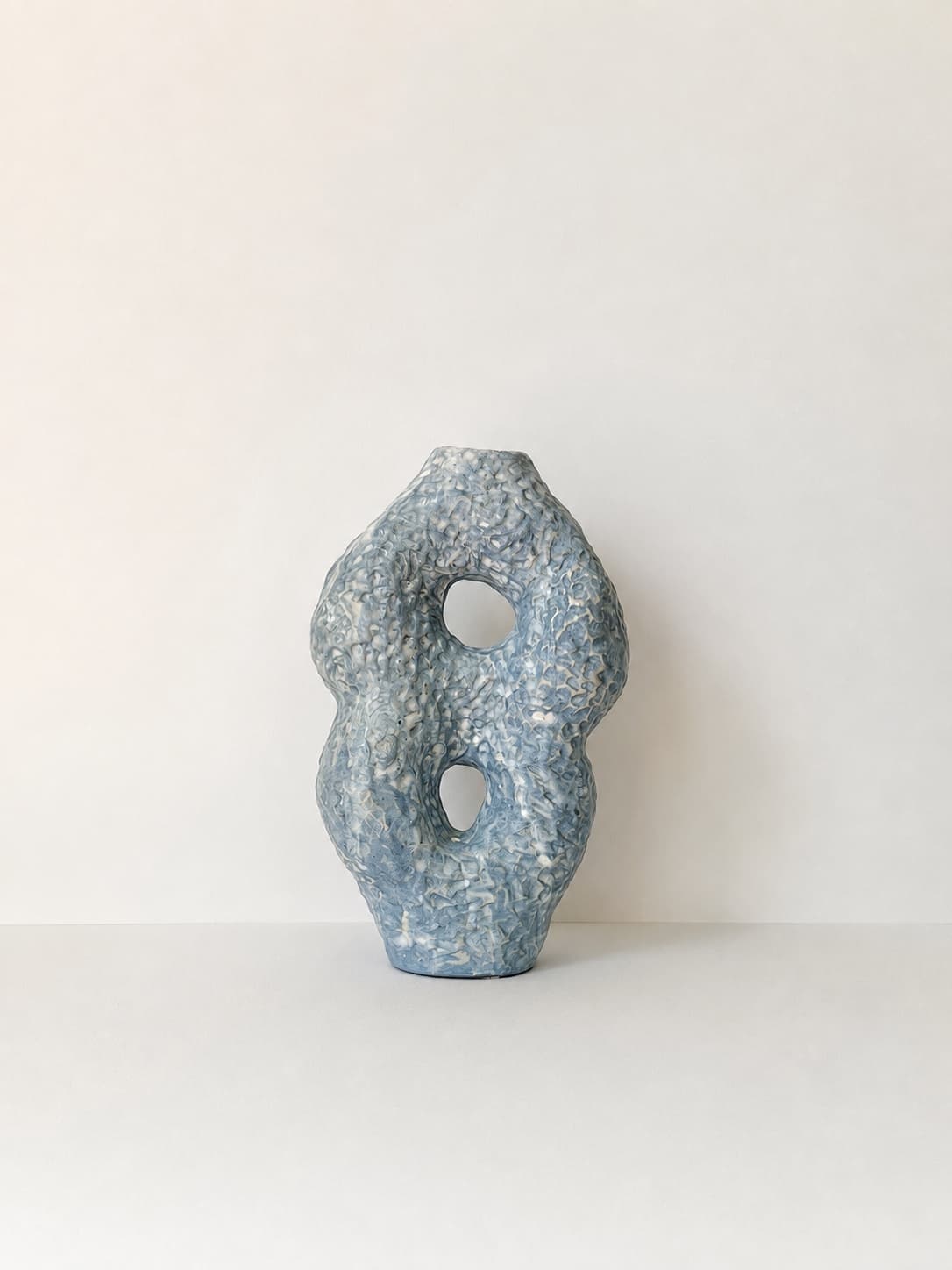 A blue and white CLÆY vessel with two openings and a textured glaze